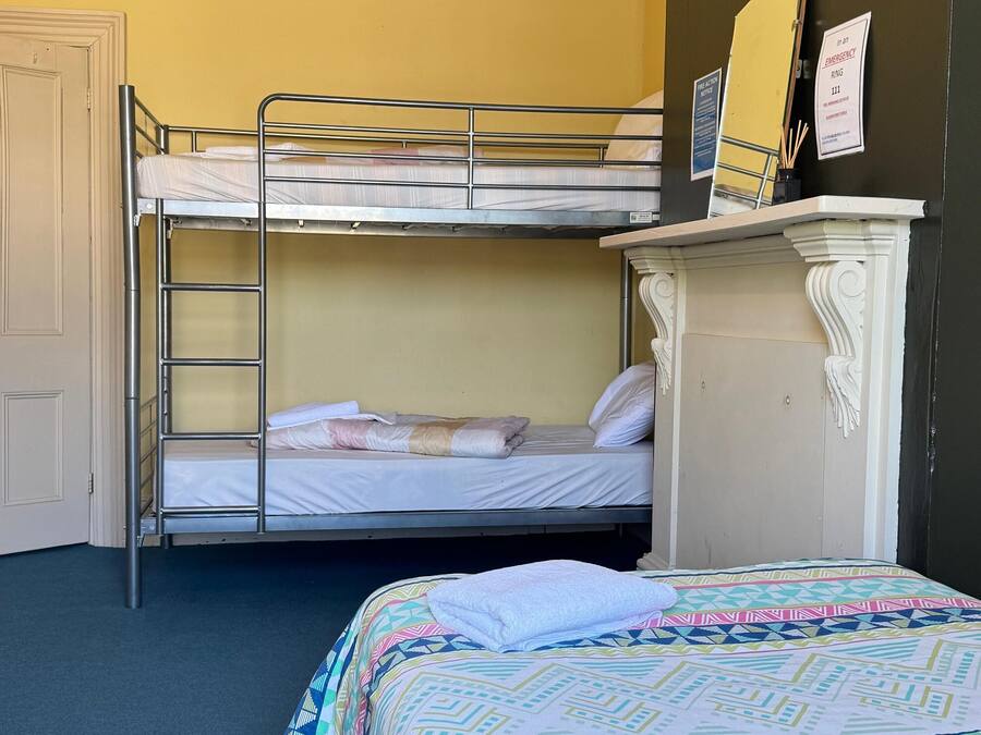 A room with bunk beds, a dresser, and a bed with a patterned bedspread.