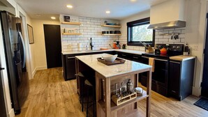 A modern kitchen with a central island, wooden flooring, and built-in appliances.