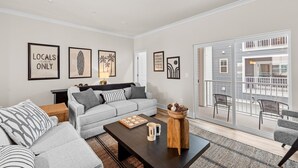 Una sala de estar moderna con un sofá gris, una mesa de centro y un balcón con mobiliario de exterior.