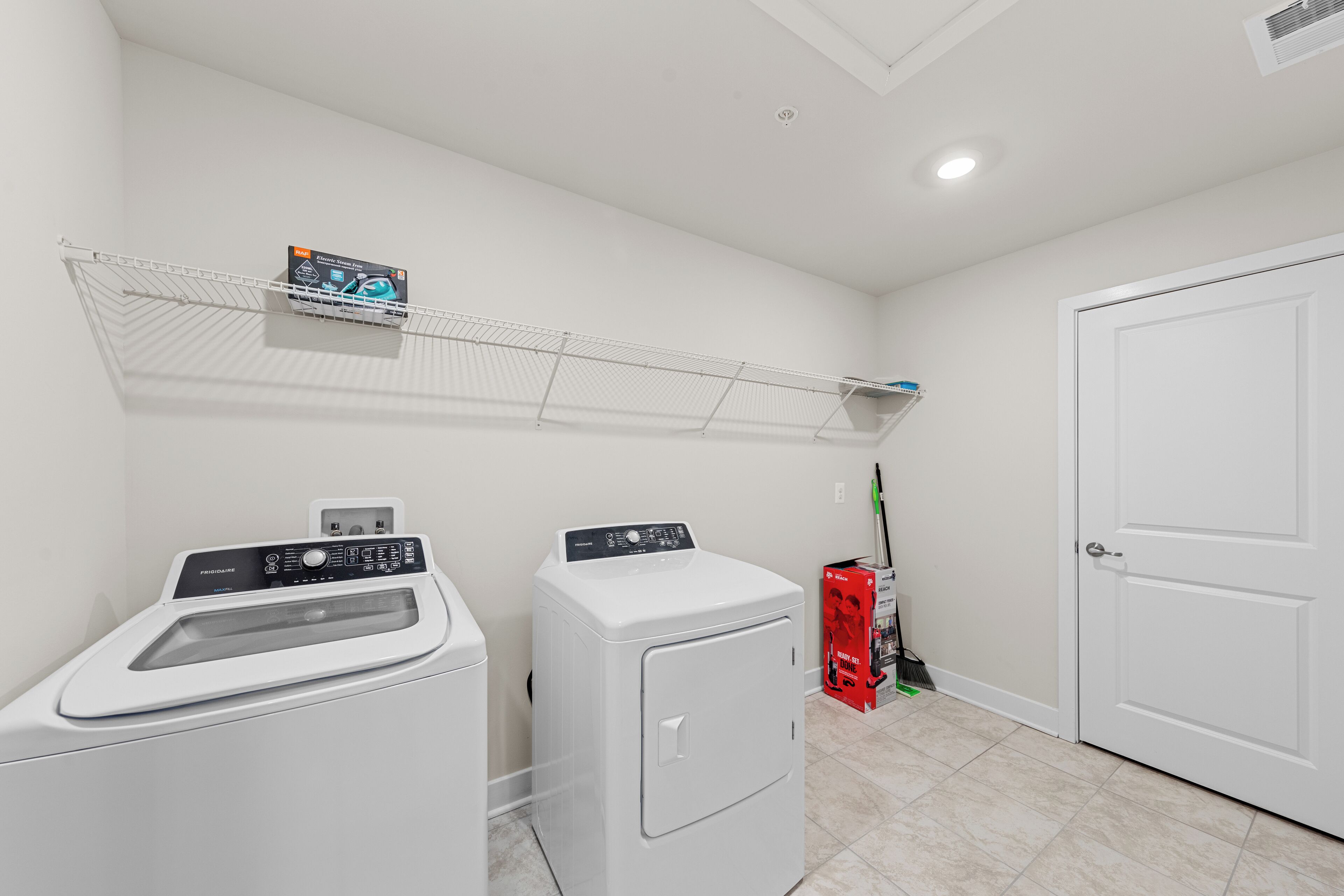 A laundry area with a washing machine, dryer, and a shelf with a laundry detergent box.