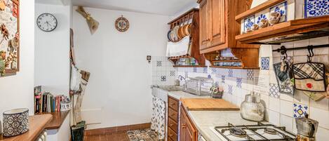 A kitchen with wooden cabinets, a gas stove, and a tiled backsplash.