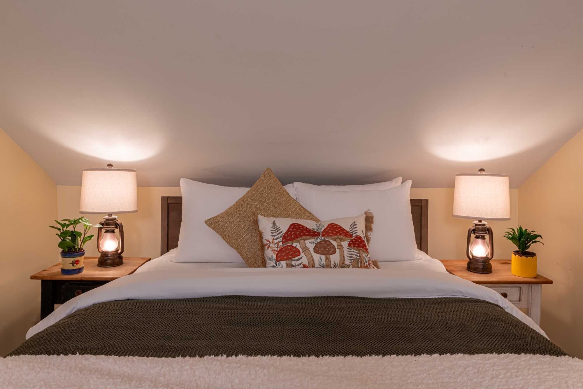 A neatly made bed with a white duvet, two bedside lamps, and decorative pillows.
