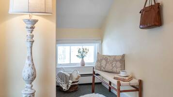 A cozy room with a lamp, a bench, a handbag, and a fur rug.