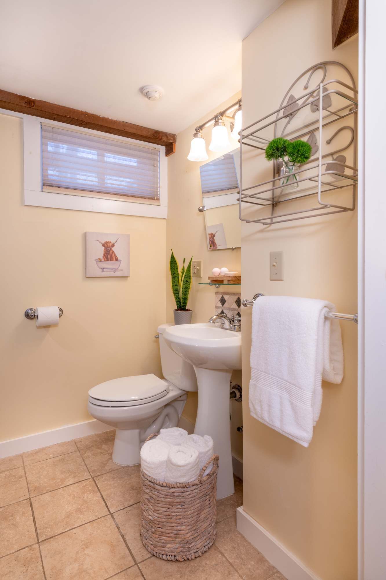 A compact bathroom with a toilet, sink, and a towel rack.
