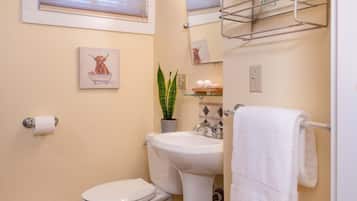 A compact bathroom with a toilet, sink, and a towel rack.