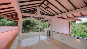 Un balcon ouvert, mais abrité, offrant une vue sur une végétation luxuriante.