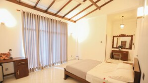 Une chambre d’hôtel avec un lit, un bureau, une chaise, un miroir et une fenêtre avec des rideaux.