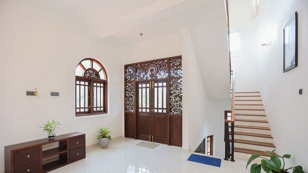 Une pièce spacieuse dotée d’un plancher ciré, d’un escalier en bois et d’une porte en bois traditionnelle aux motifs complexes.