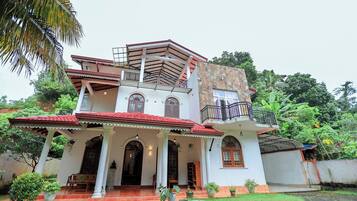 Traditional house with a balcony and lush surroundings.