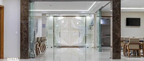 Un hall d’hôtel doté d’une entrée avec une porte en verre, d’un comptoir de réception et d’un espace détente avec des fauteuils.