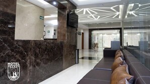 Eine moderne Hotelhalle mit einer Rezeption, einer Sitzecke und einer Glastrennwand.