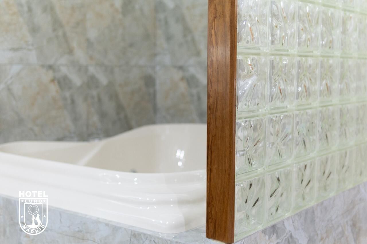 A bathtub with a wooden frame and a glass panel with a floral pattern.