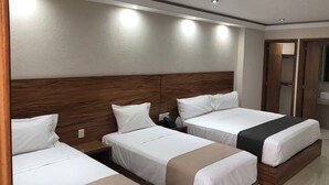 Ein Hotelzimmer mit drei Einzelbetten, einem Holz-Kopfteil und einem Spiegel an der Wand.
