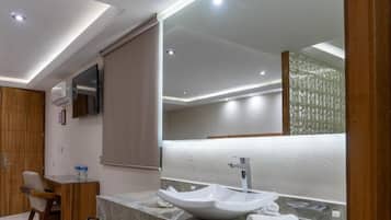 Un baño moderno con un espejo grande, un lavamanos blanco y una silla de madera.