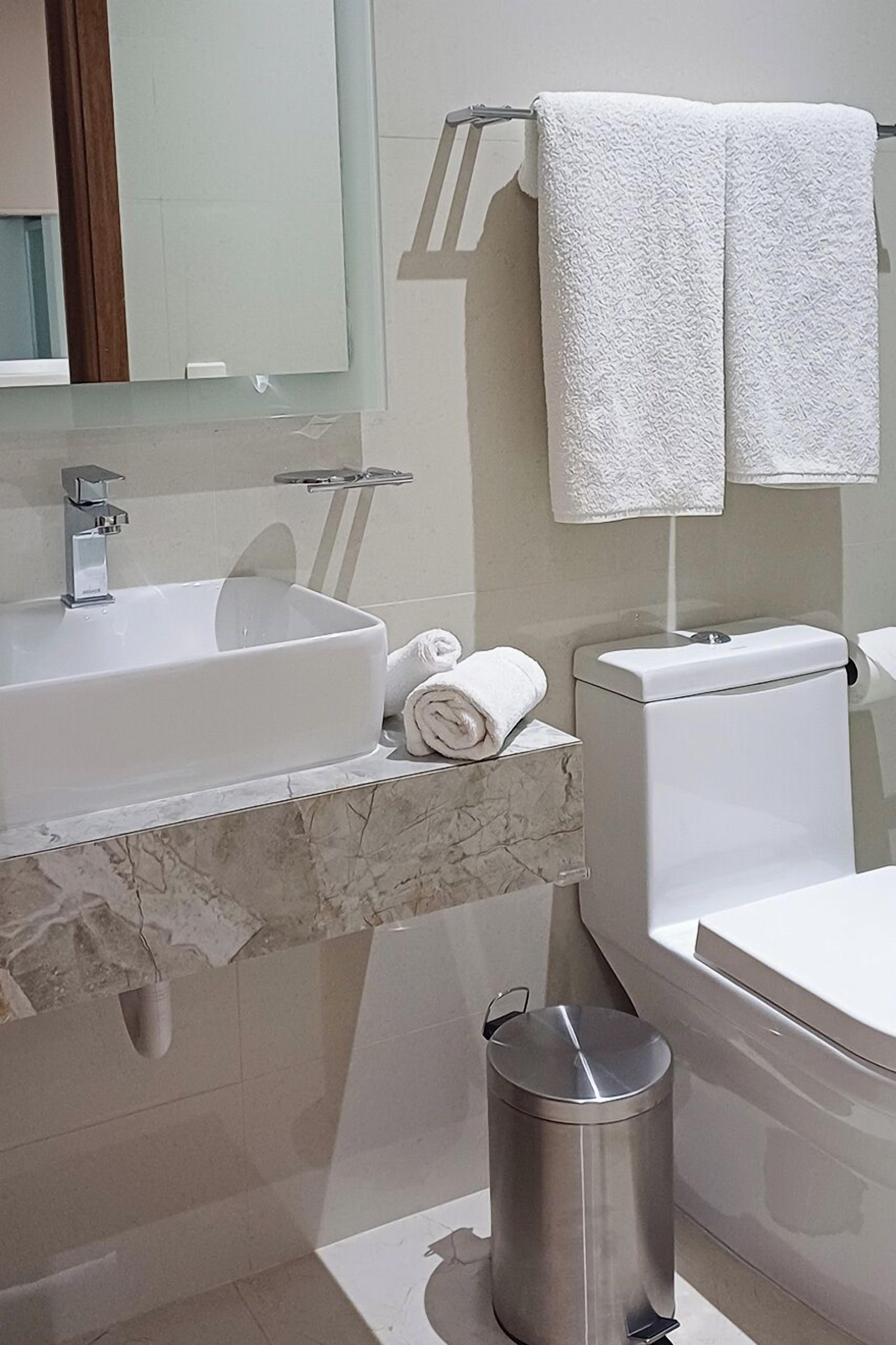 Ein modernes Badezimmer mit einem мраморному Waschbecken, einer Toilette und einem Mülleimer.