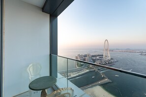 Un balcon offrant une vue dégagée sur une grande roue, une étendue d’eau et le paysage urbain au loin.