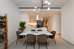Een moderne keuken met een centraal eiland, witte kasten en een zwarte koelkast.