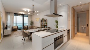 Une cuisine moderne dotée d’un îlot central, d’un four encastré et d’une grande fenêtre donnant sur la ville.