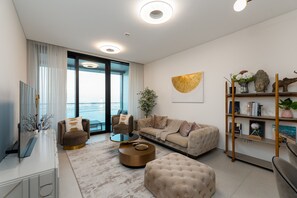 Een moderne woonkamer met een bank, fauteuils, een salontafel en een boekenkast.