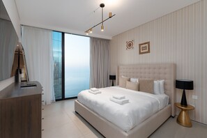 Une chambre d’hôtel moderne, dotée d’un grand lit, d’un bureau, d’une chaise, d’une lampe et offrant une vue sur la ville par la fenêtre.
