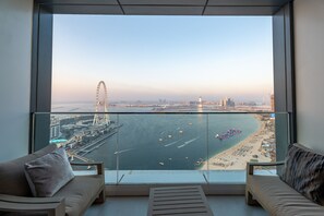 Un balcón con vistas a un horizonte urbano, una noria y una playa con barcos.