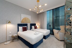 Een moderne hotelkamer met twee bedden, een groot raam en een kroonluchter.