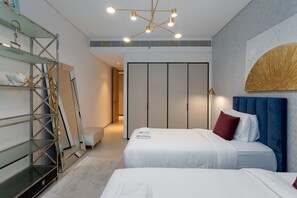 Una habitación de hotel moderna con dos camas, una estantería de vidrio, un espejo grande y una lámpara de techo original.