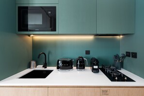 A modern kitchen with a microwave, toaster, kettle, and gas stove.