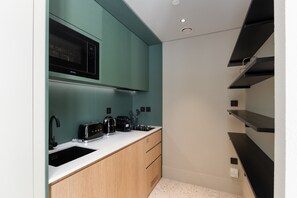 A compact kitchen with a microwave, toaster, and coffee maker on a white countertop.