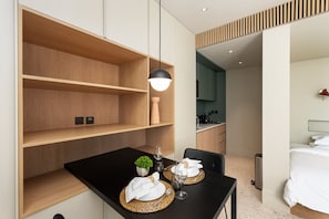 Une chambre d’hôtel moderne comprenant un coin repas, un lit et une kitchenette.