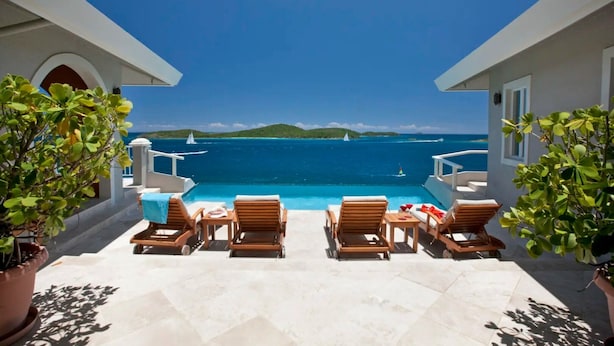 A poolside area with lounge chairs and a view of the sea.