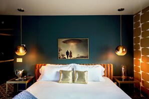 Habitación de hotel con cama, dos lámparas de noche, un cuadro y pared decorada.