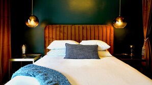 Et hotelværelse med en stor seng, to sengeborde, en natbord og en lampe på væggen.
