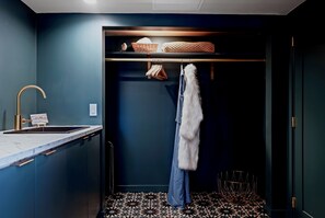 Un baño moderno con una pared azul oscuro, un lavamanos blanco y un perchero con una toalla mullida.