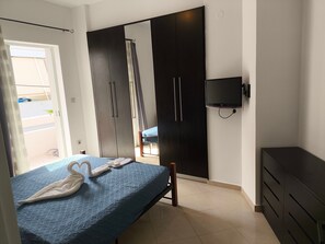Une chambre à coucher avec un lit, une armoire, une télévision et un balcon.