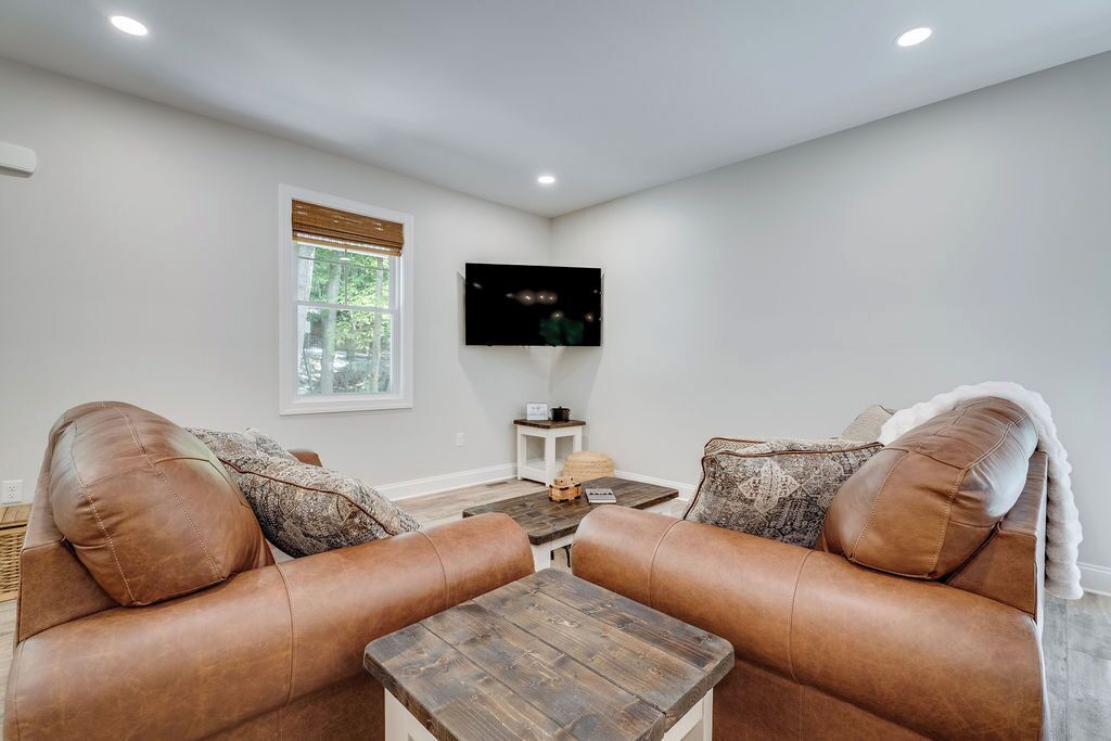 A living room with two leather sofas, a wooden coffee table, and a television mounted on the wall.
