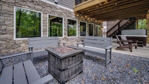Eine Terrasse mit Steinmauern, Holzbanken und einem Feuerkorb.