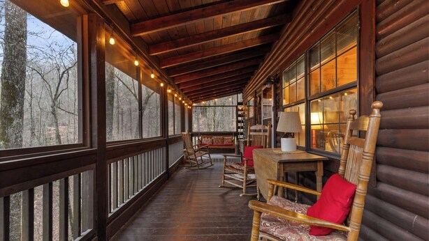 A wooden deck with a wooden table and chairs, large windows, and string lights. - Mountain Views, Hot Tub + More! - Deer Crossing (Ellijay)
