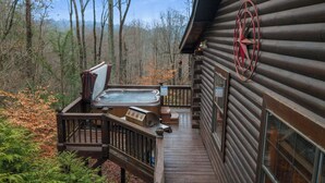 A wooden cabin with a hot tub on a deck, surrounded by trees. - Mountain Views, Hot Tub + More! - Deer Crossing (Ellijay)