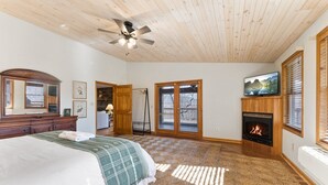 Ein Schlafzimmer mit einem Bett, einem Kamin, einem Fernseher und einem Deckenventilator.