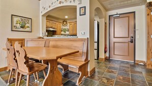 A wooden dining table with benches, a kitchen area with wooden cabinets, a refrigerator, and a door with a handle. - Charming Midway Villa~Pool, Tubing, Skiing, & Ice Castles Villa 2057-1 (Midway)