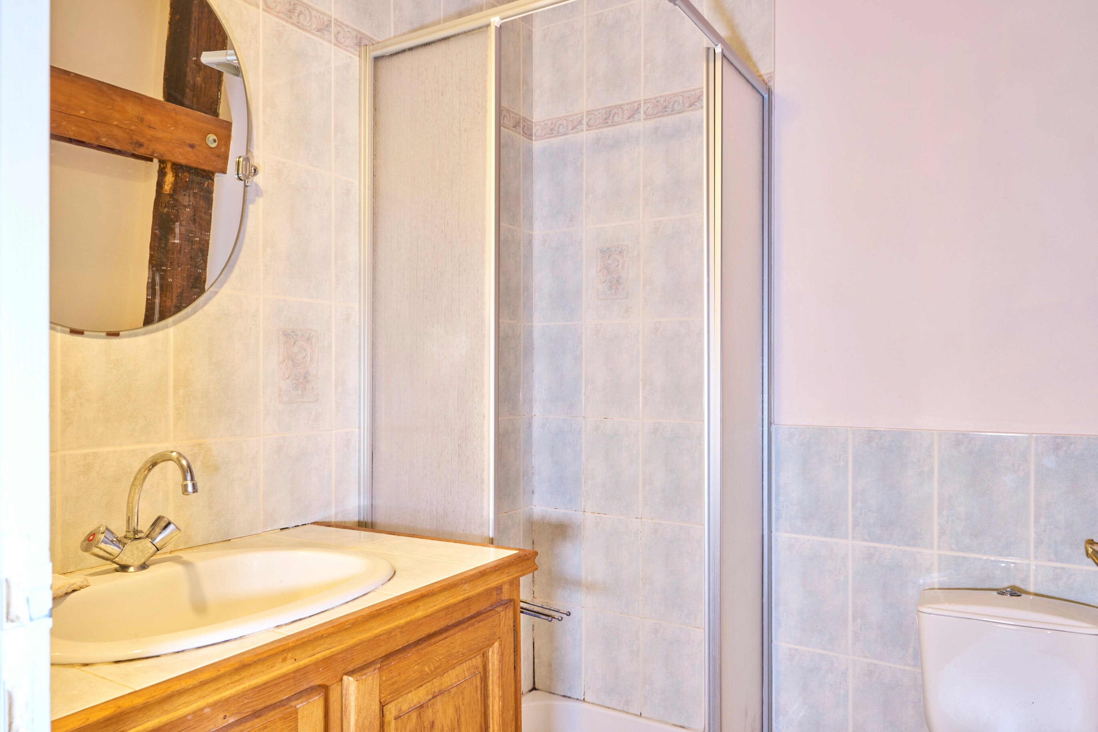 A bathroom with a sink, mirror, and shower.