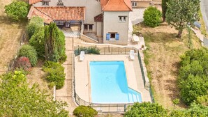 A large house with a swimming pool, surrounded by trees and a garden.