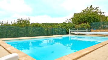 A rectangular swimming pool with a clear blue water surface, surrounded by a beige tiled deck.
