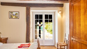 A bedroom with a bed, a chair, a wooden door, and a window.
