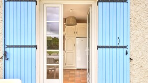 A doorway leading to a kitchen with white cabinets and a white refrigerator.