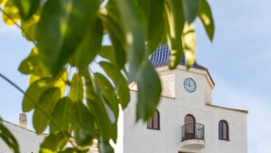 Un edificio con reloj, balcones y tejado de tejas.