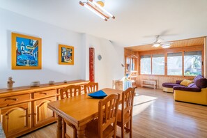 A dining area with wooden furniture, a sofa, and artwork on the walls.