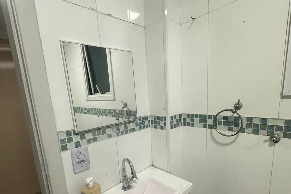 Un baño con un lavamanos blanco, un espejo y una zona de ducha.