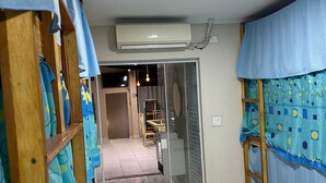 A room with a tiled floor, a sliding glass door leading to a dining area, and an air conditioning unit mounted on the wall. - Moriah Pousada e  Hostel (Praia Grande)